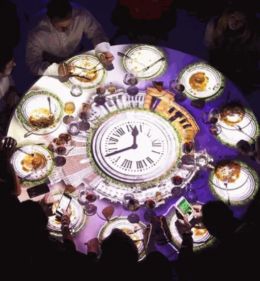 Detalle de una mesa de gala con un reloj proyectado mediante video mapping
