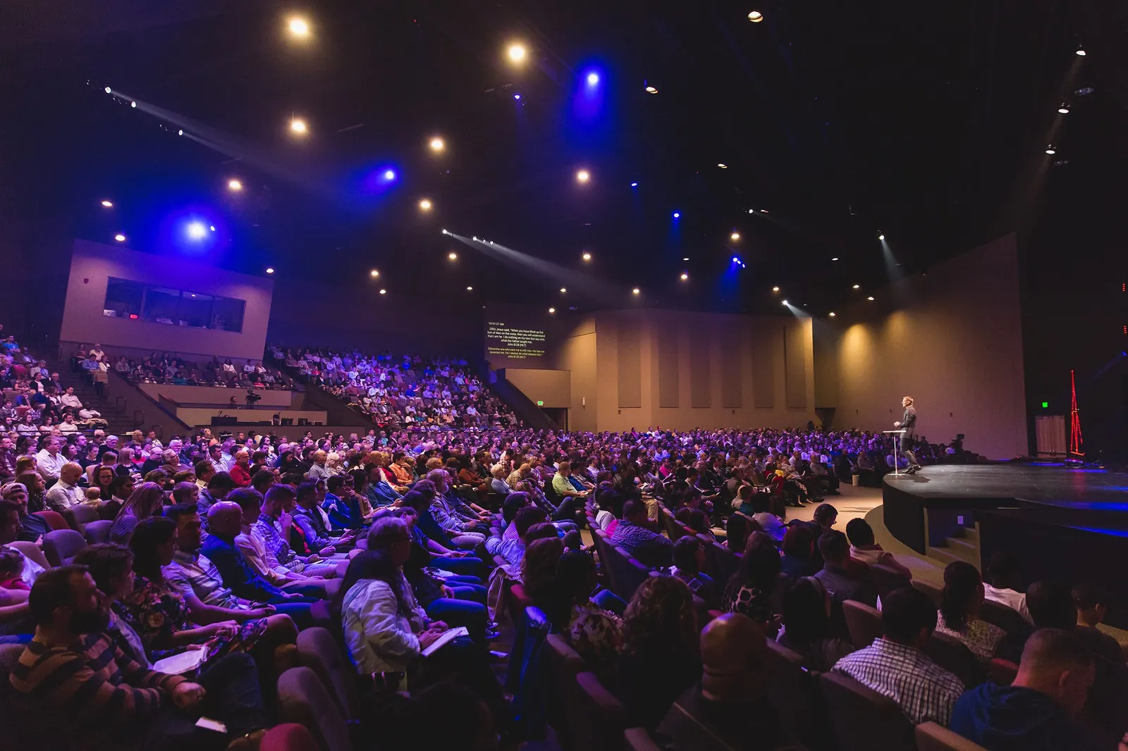 Auditorio lleno durante un evento corporativo con iluminación escénica