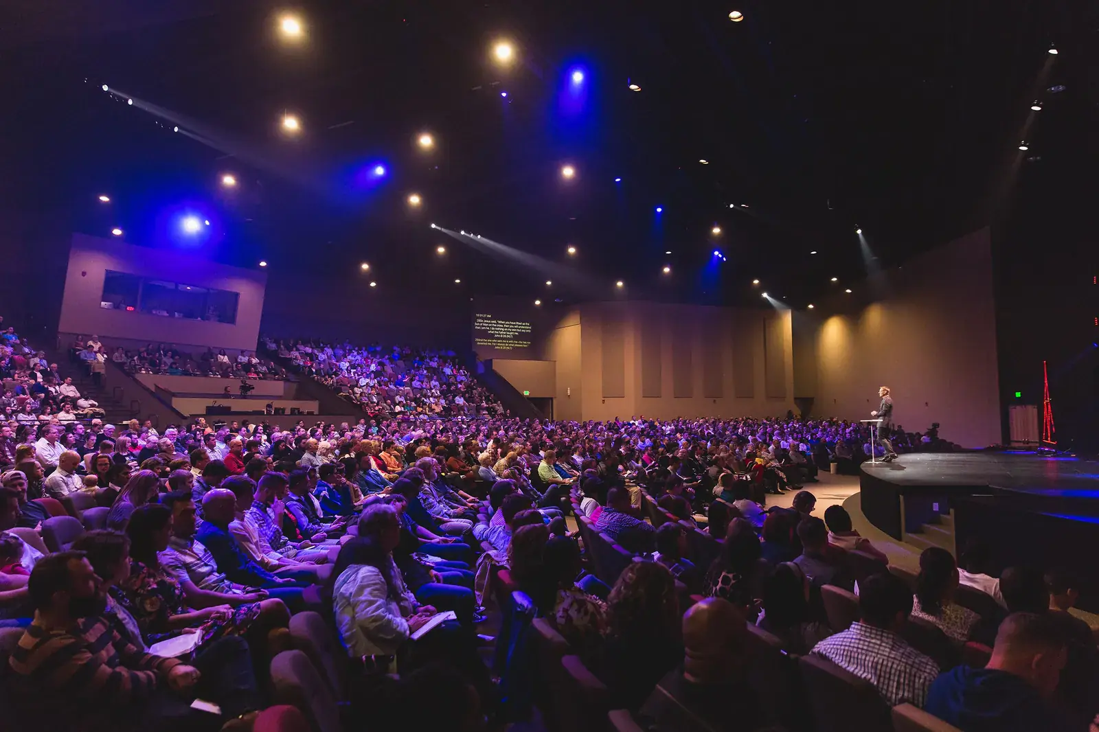 Auditorio lleno durante un evento corporativo con iluminación escénica