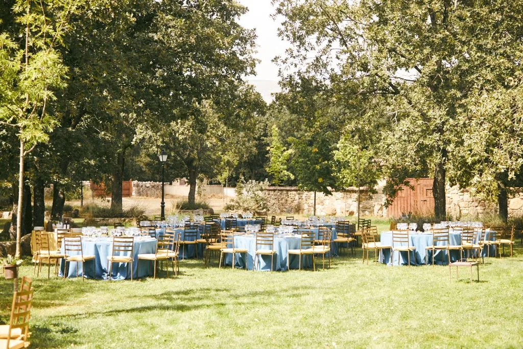 Mesas del banquete al aire libre bajo los árboles de la finca de Robledo, en Rascafría