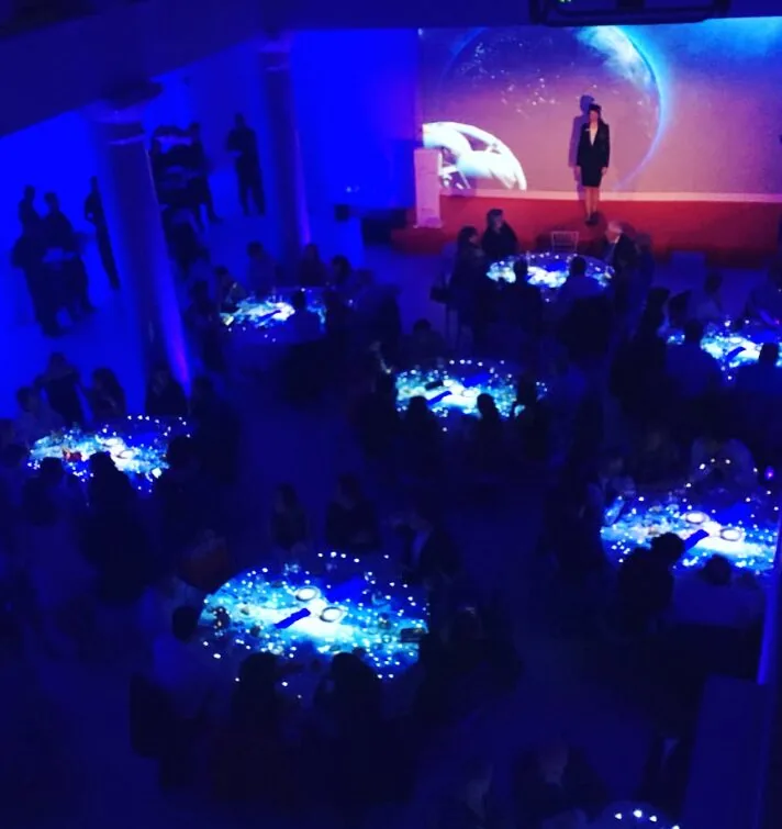 Mesa con proyección del lema del evento y pantalla al fondo