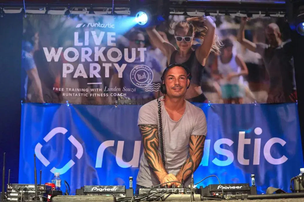 DJ en la cabina bajo el cartel de la Live Workout Party de Runtastic