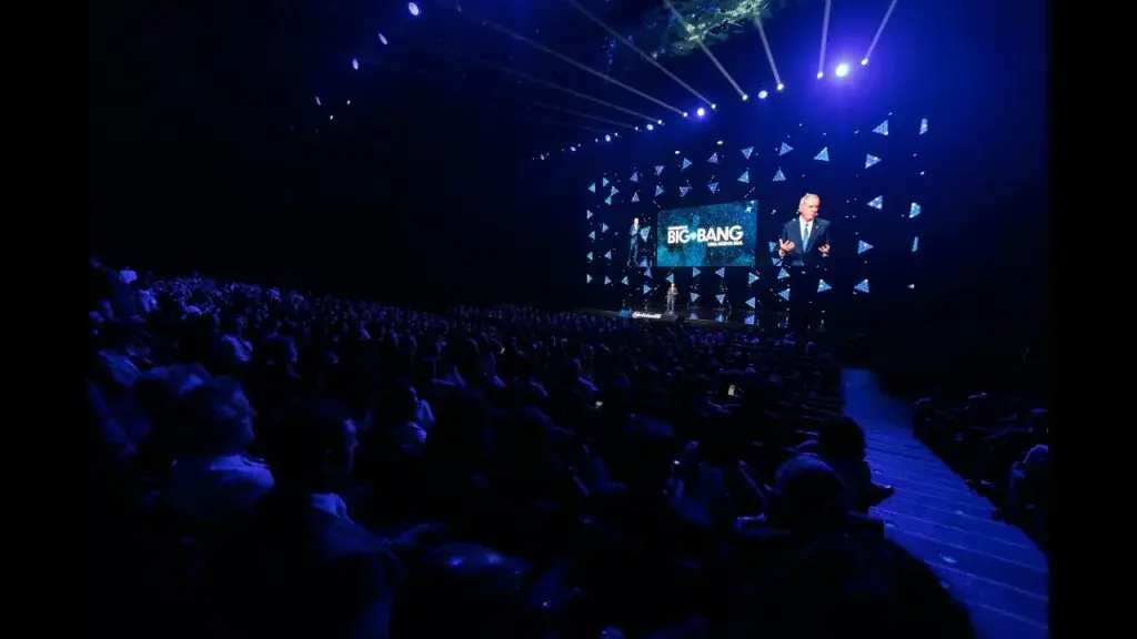 Vista de la sala durante una intervención, con el escenario iluminado al fondo