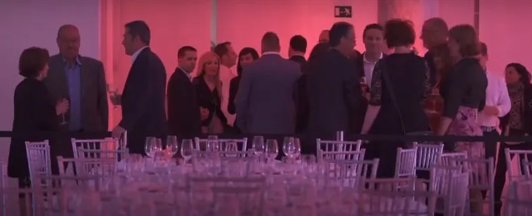 Invitados conversando en el cóctel del 25 aniversario de Serviat con iluminación en rojo