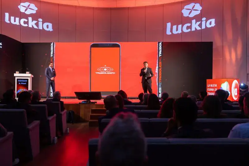 Presentación en el escenario de una convención con pantallas en rojo