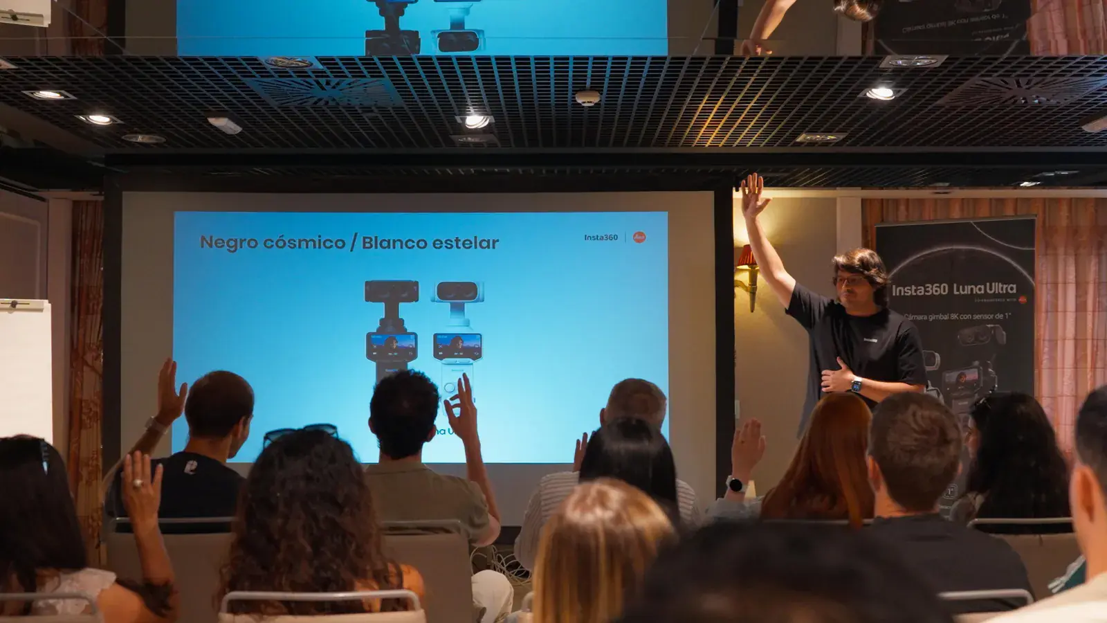 Presentación de producto ante un público que levanta la mano en una sala