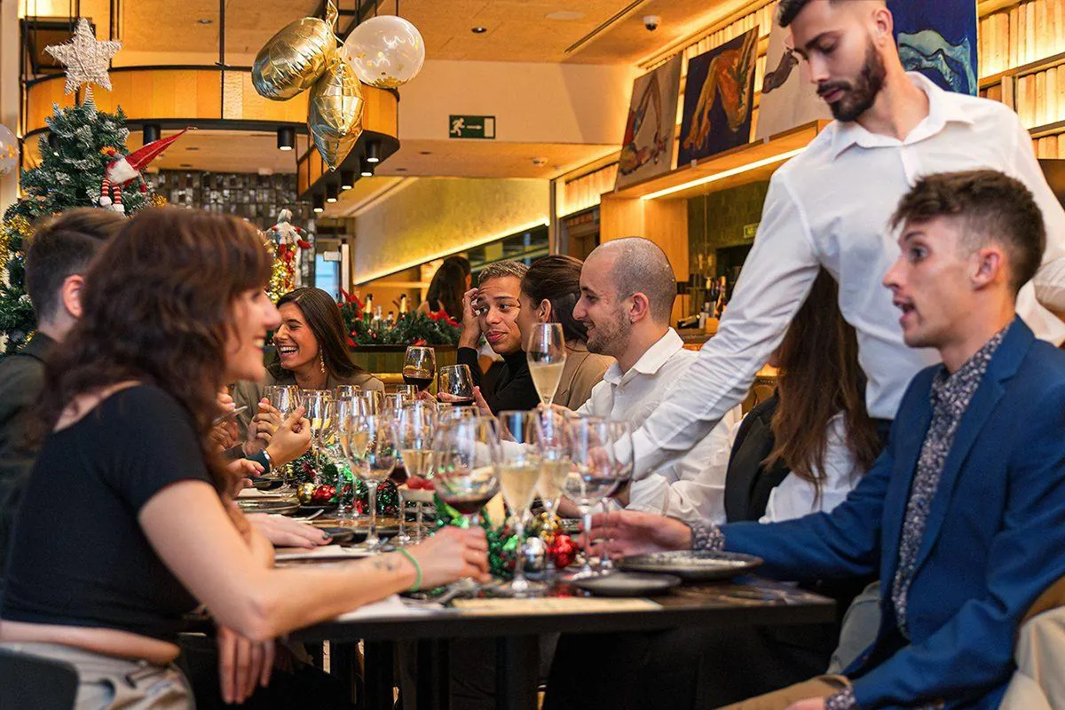 Cena de Navidad de empresa en un restaurante con camareros sirviendo