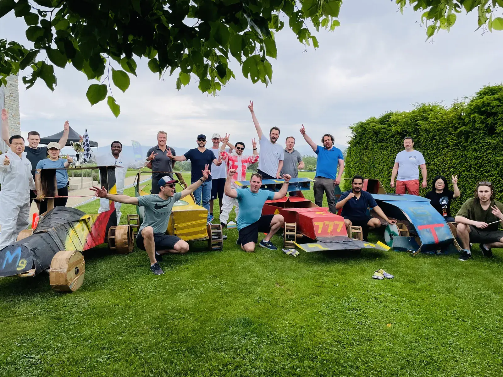 Equipos con coches de cartón en una actividad de team building en un jardín