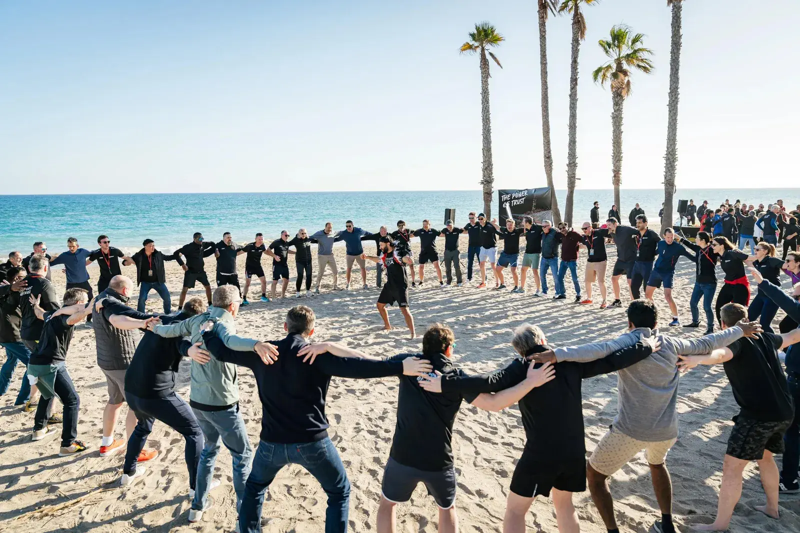 Grupo formando un círculo en la playa durante un team building